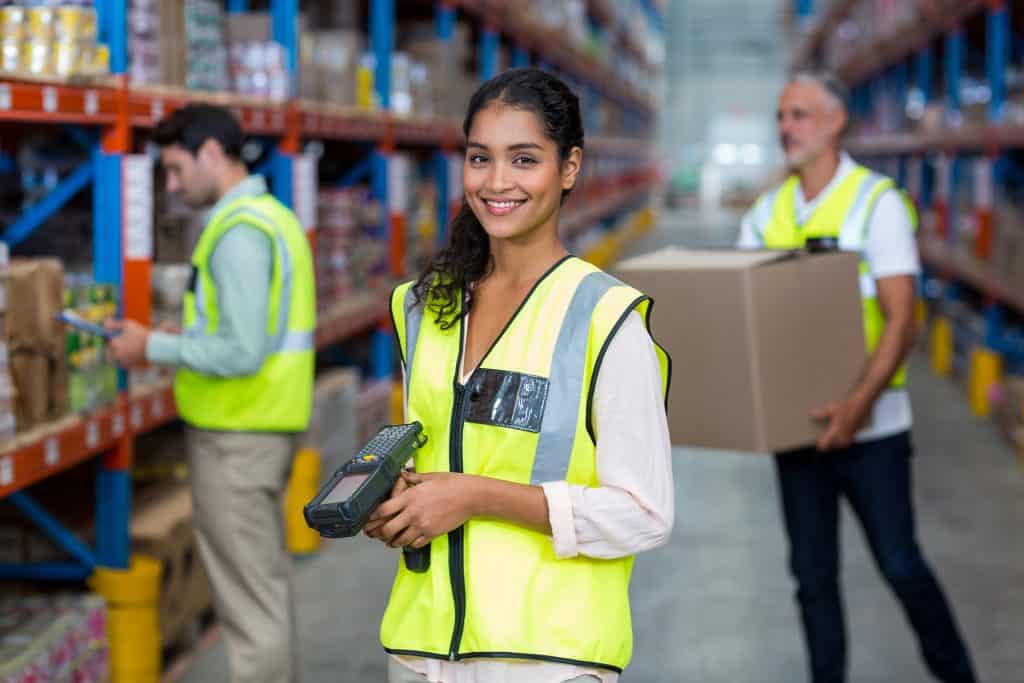 Portrait of female warehouse worker standing with barcode scanner in warehouse
